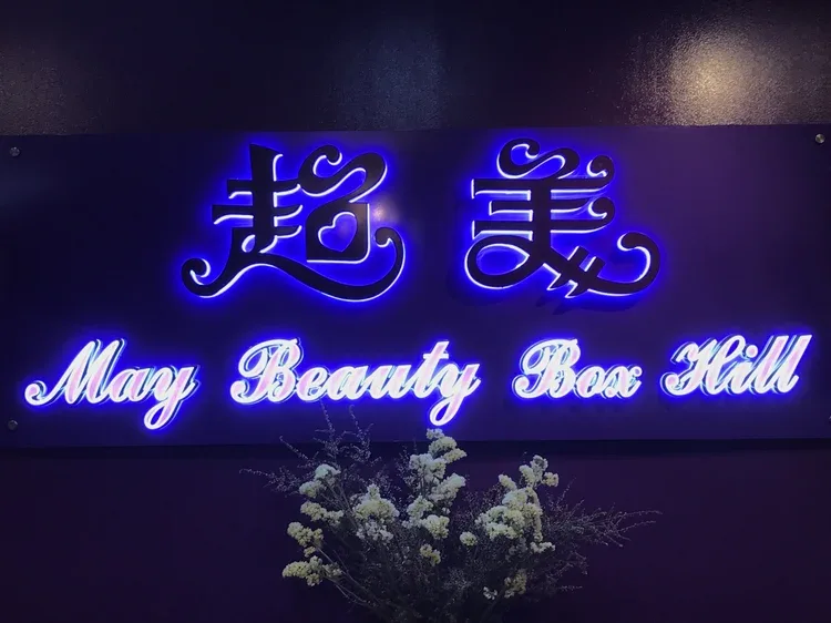 May Beauty Box Hill illuminated interior sign — blue-lit script reading 超美 / May Beauty Box Hill with dried-flower posy